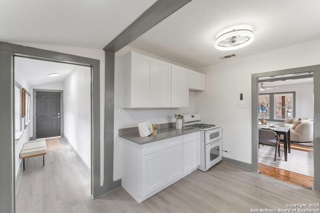 kitchen featuring white cabinetry, double oven range, vaulted ceiling, and light wood-type flooring