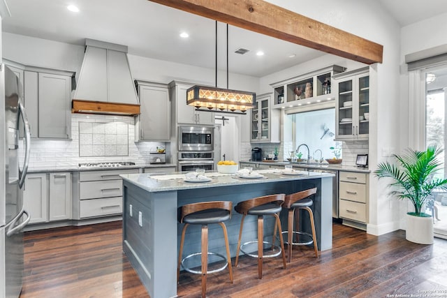 kitchen with a kitchen island, premium range hood, appliances with stainless steel finishes, and hanging light fixtures