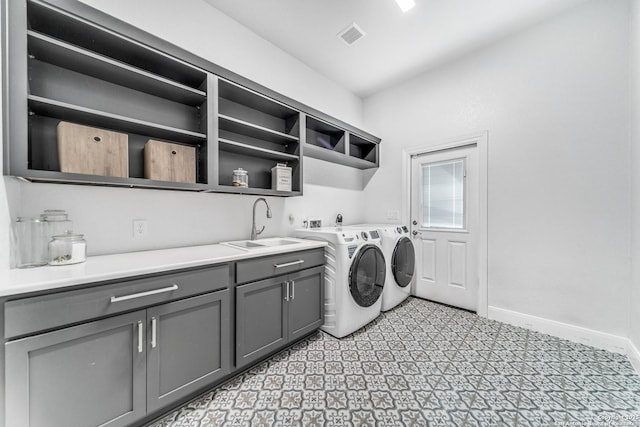 clothes washing area featuring cabinets, sink, and washing machine and clothes dryer