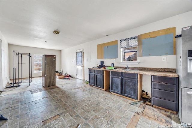 kitchen with dark brown cabinetry, stainless steel fridge with ice dispenser, and sink