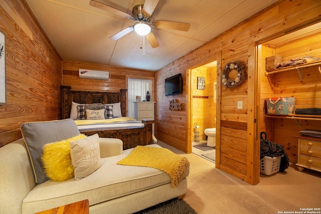 bedroom featuring ensuite bath, wooden walls, light carpet, and a wall unit AC