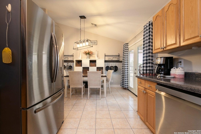 kitchen featuring light tile patterned flooring, lofted ceiling, appliances with stainless steel finishes, and decorative light fixtures