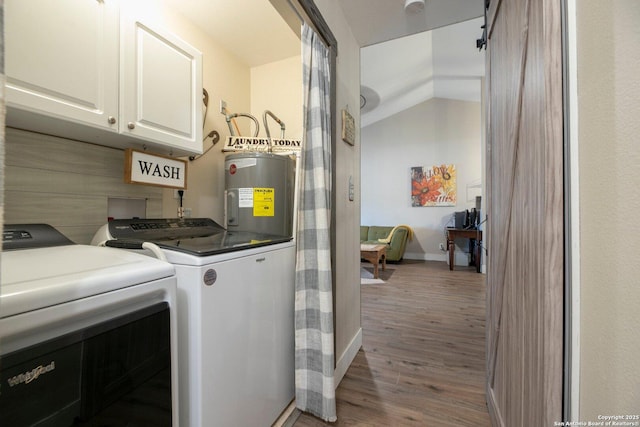 laundry area with water heater, cabinets, washing machine and dryer, a barn door, and light wood-type flooring