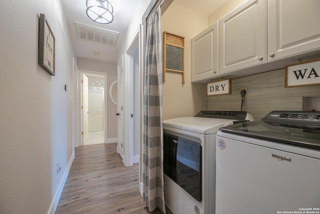 laundry area with cabinets, separate washer and dryer, and light hardwood / wood-style floors