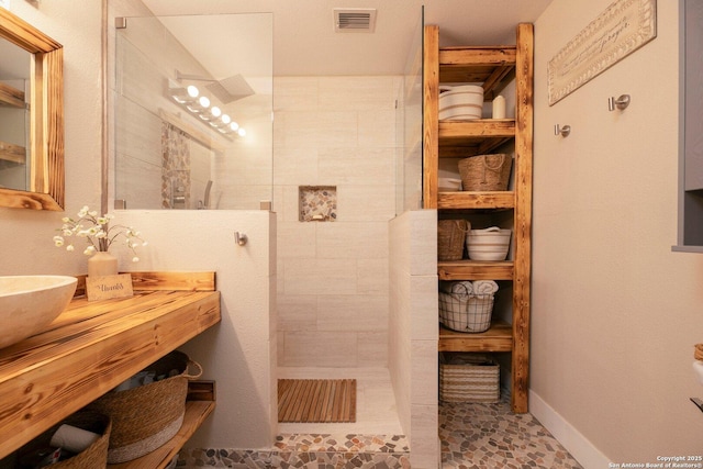 bathroom featuring tiled shower and vanity