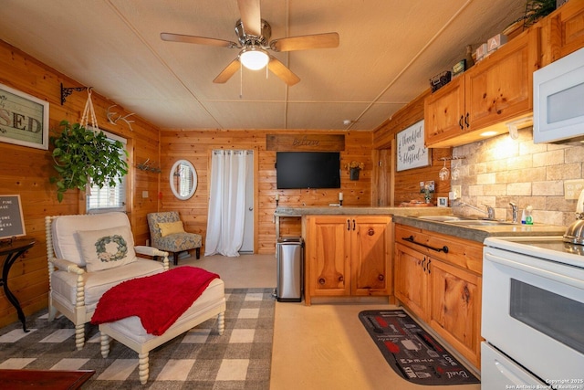 kitchen featuring sink, white appliances, ceiling fan, backsplash, and wooden walls