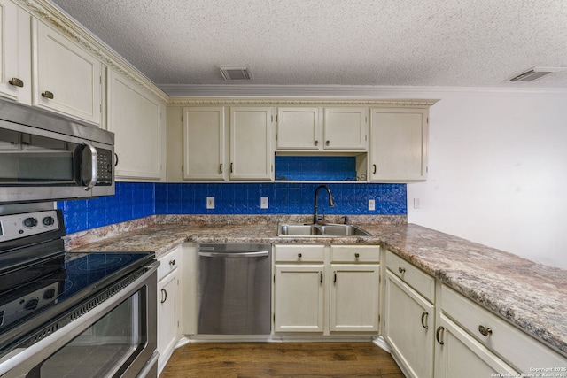 kitchen featuring sink, crown molding, stainless steel appliances, dark hardwood / wood-style floors, and cream cabinets