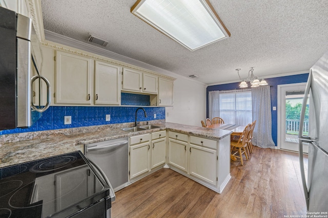 kitchen featuring sink, cream cabinetry, kitchen peninsula, and appliances with stainless steel finishes