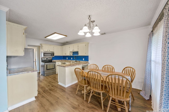 kitchen featuring pendant lighting, tasteful backsplash, a notable chandelier, stainless steel appliances, and light hardwood / wood-style flooring