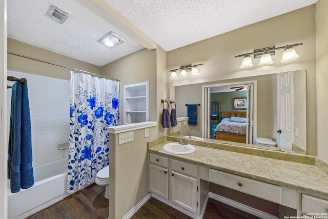 full bathroom featuring shower / tub combo, vanity, wood-type flooring, a textured ceiling, and toilet