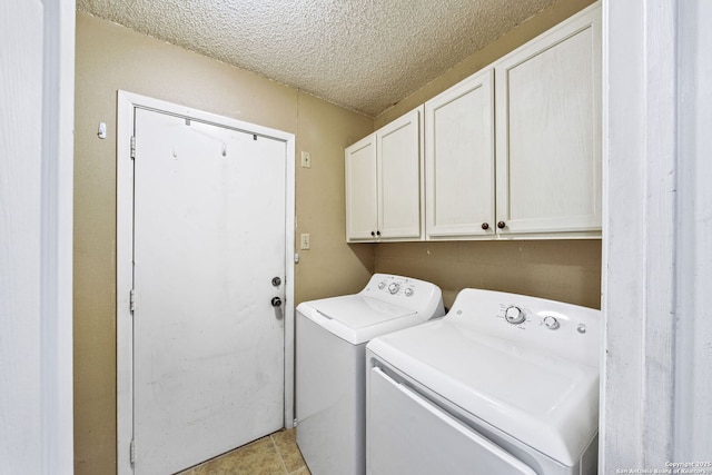 laundry area featuring cabinets, washing machine and clothes dryer, and a textured ceiling