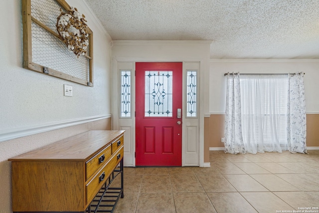 tiled entryway featuring ornamental molding and a textured ceiling