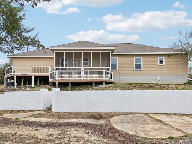 rear view of house featuring a sunroom and a deck