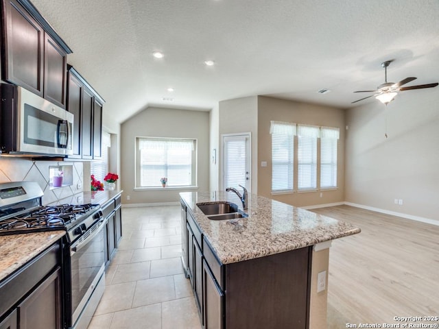 kitchen with sink, dark brown cabinets, stainless steel appliances, and an island with sink