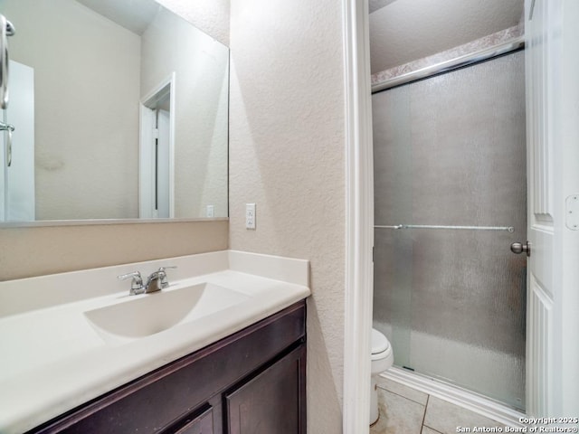 bathroom featuring tile patterned flooring, vanity, walk in shower, and toilet