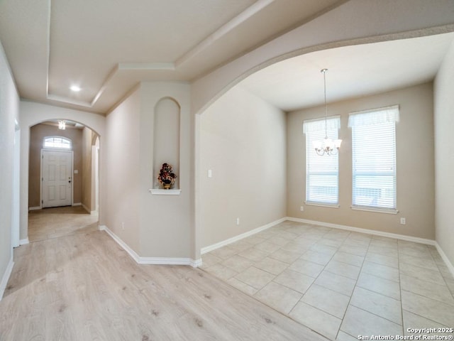 foyer entrance featuring a notable chandelier, light hardwood / wood-style floors, and a raised ceiling