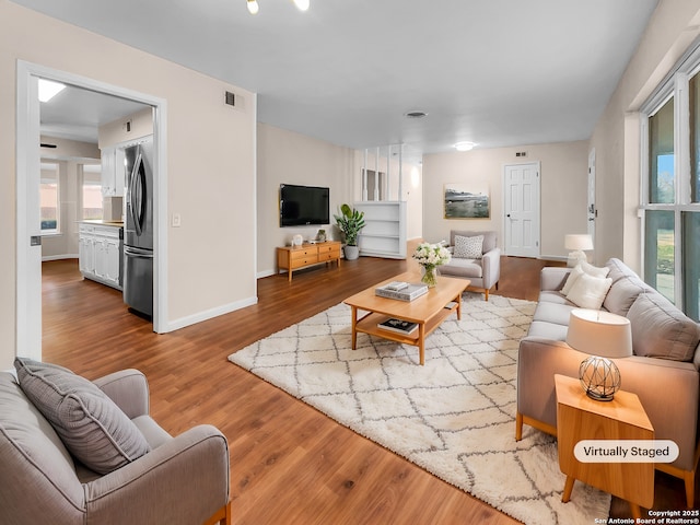 living room featuring visible vents, baseboards, and wood finished floors