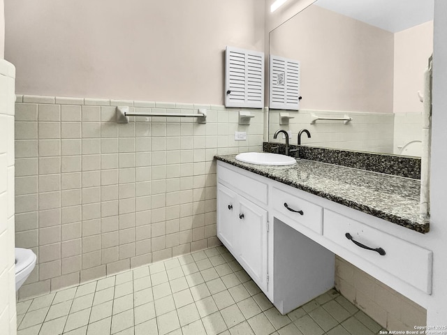 bathroom with vanity, toilet, tile patterned flooring, and tile walls