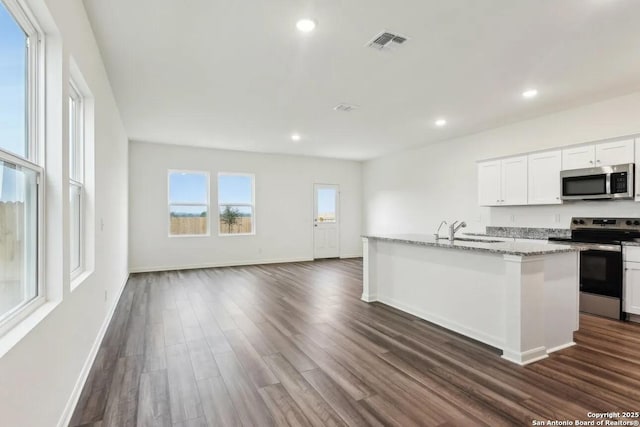 kitchen featuring sink, dark wood-type flooring, appliances with stainless steel finishes, a kitchen island with sink, and white cabinets