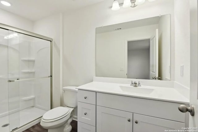 bathroom featuring toilet, vanity, and a shower with shower door