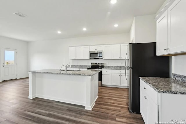 kitchen with sink, white cabinetry, appliances with stainless steel finishes, dark stone counters, and a kitchen island with sink