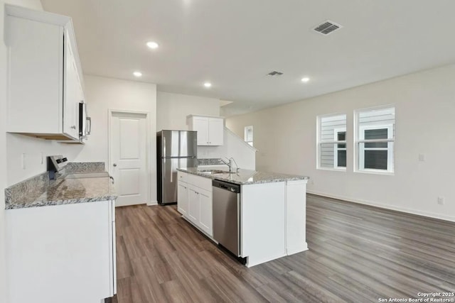 kitchen with sink, white cabinetry, stainless steel appliances, a center island with sink, and dark hardwood / wood-style flooring