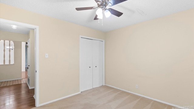 unfurnished bedroom featuring light carpet, ceiling fan, a closet, and a textured ceiling