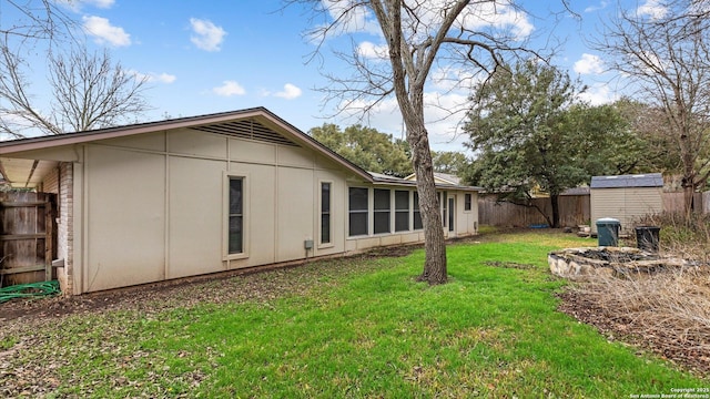 rear view of property featuring a storage shed and a lawn