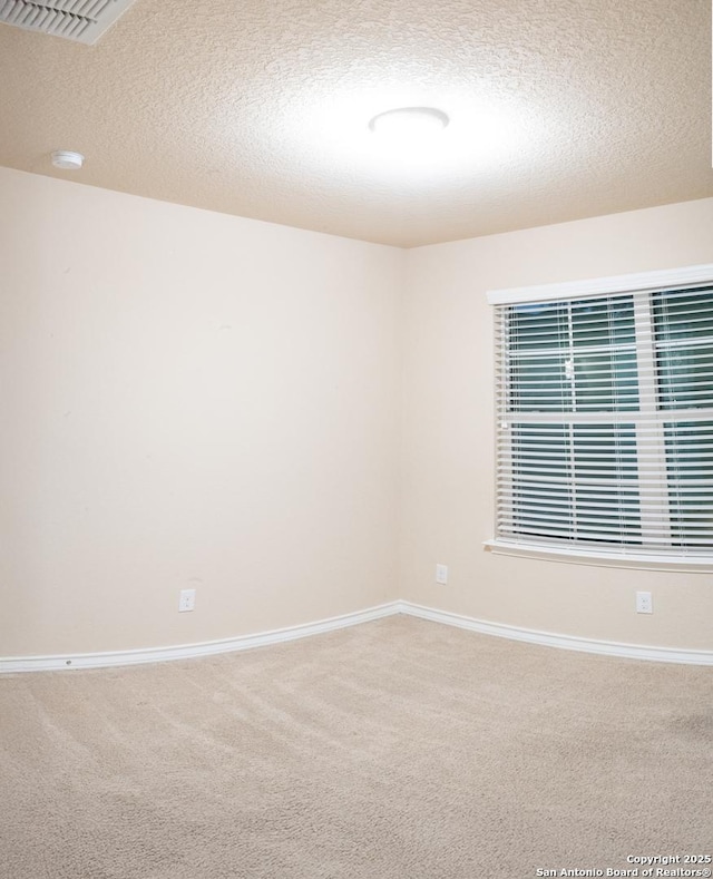 unfurnished room featuring carpet and a textured ceiling