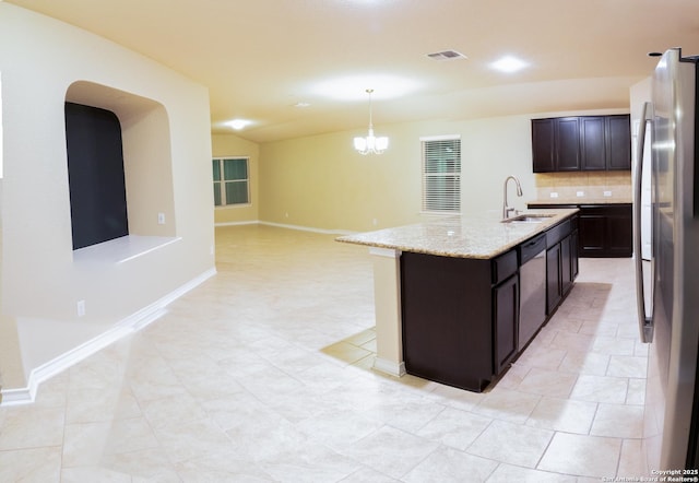 kitchen with appliances with stainless steel finishes, pendant lighting, sink, light stone counters, and a center island with sink