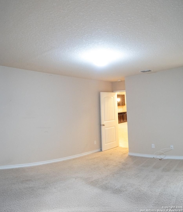 empty room with light colored carpet and a textured ceiling