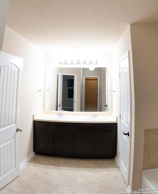 bathroom featuring vanity, tile patterned floors, and a textured ceiling