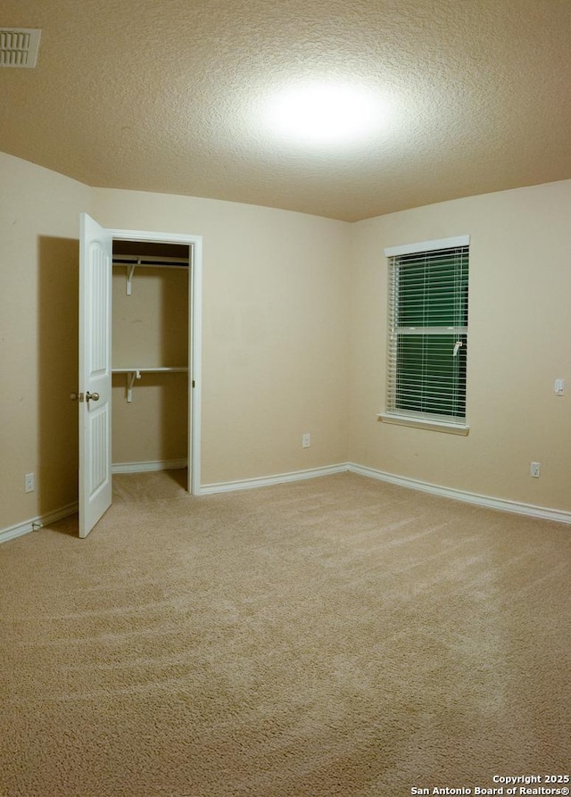 unfurnished bedroom with light carpet, a closet, and a textured ceiling