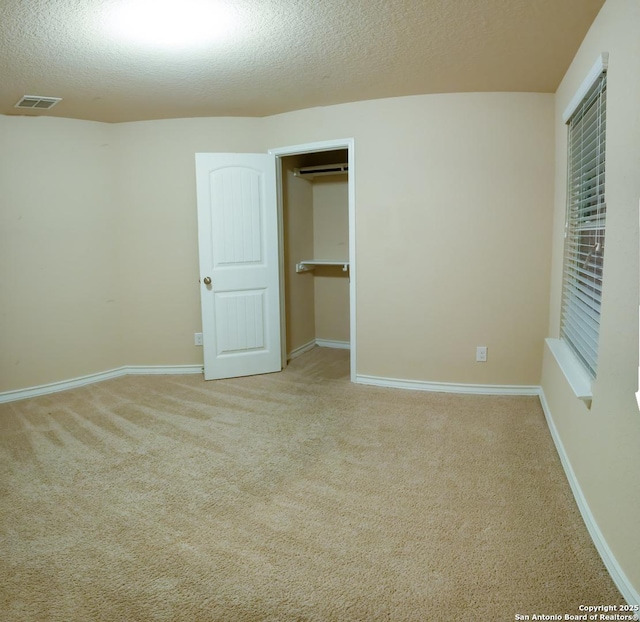 unfurnished bedroom with light carpet, a textured ceiling, and a closet