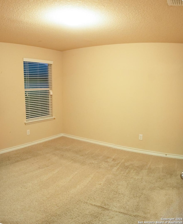 empty room with carpet floors and a textured ceiling