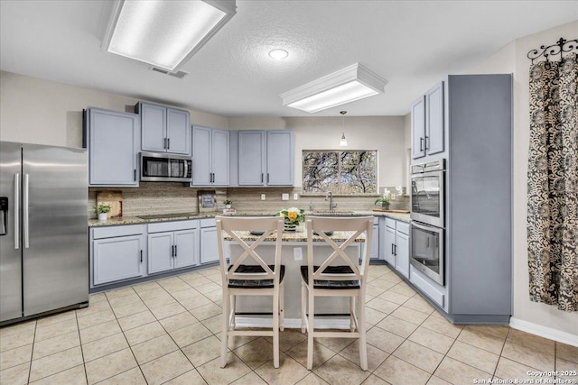 kitchen with a breakfast bar, a center island, light tile patterned floors, stainless steel appliances, and backsplash