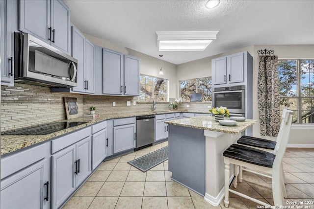 kitchen with stainless steel appliances, light tile patterned flooring, light stone counters, and a kitchen breakfast bar