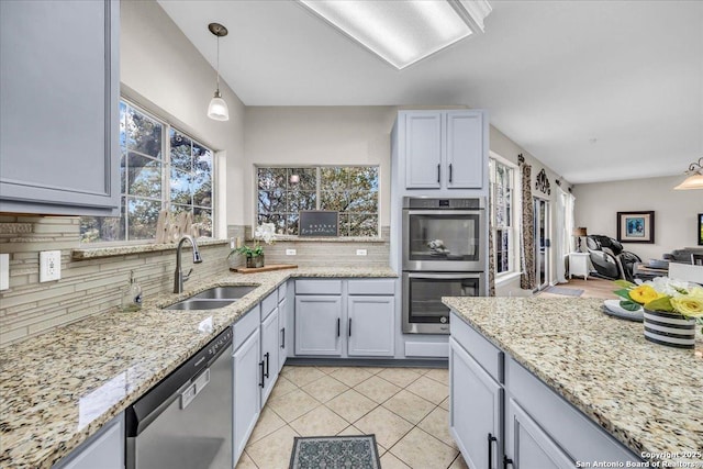 kitchen featuring appliances with stainless steel finishes, decorative light fixtures, sink, backsplash, and light tile patterned floors