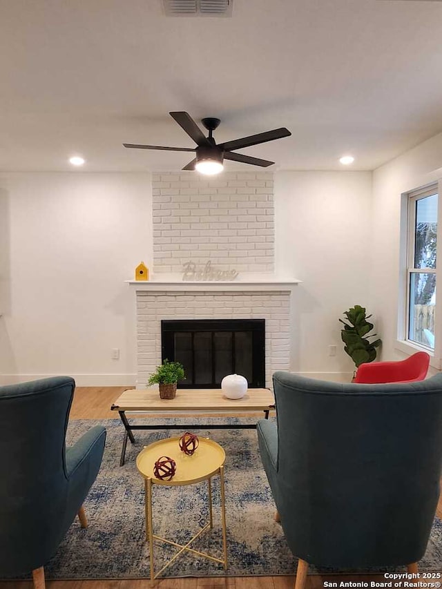 living room with hardwood / wood-style flooring, ceiling fan, and a fireplace