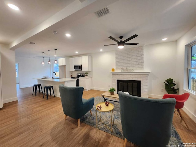 living room with sink, a fireplace, and light hardwood / wood-style flooring