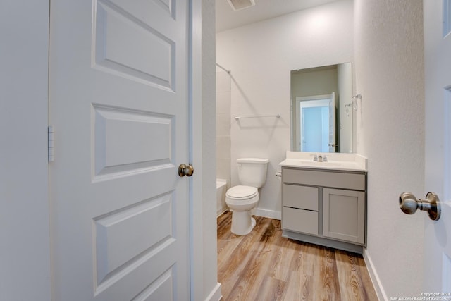 full bathroom featuring hardwood / wood-style flooring, vanity, tub / shower combination, and toilet