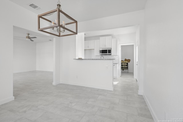 kitchen featuring white cabinetry, ceiling fan with notable chandelier, light stone counters, and kitchen peninsula