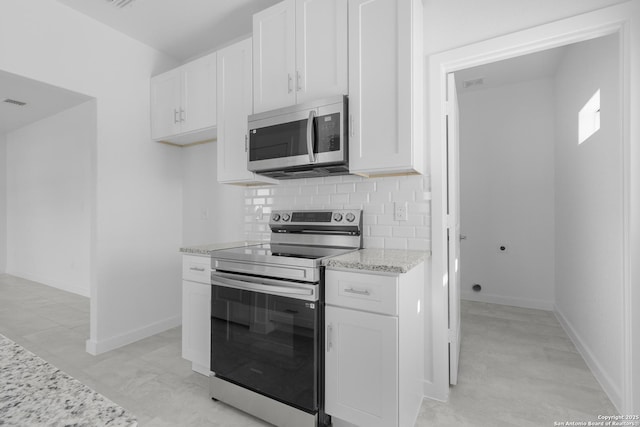 kitchen featuring white cabinetry, appliances with stainless steel finishes, light stone countertops, and tasteful backsplash