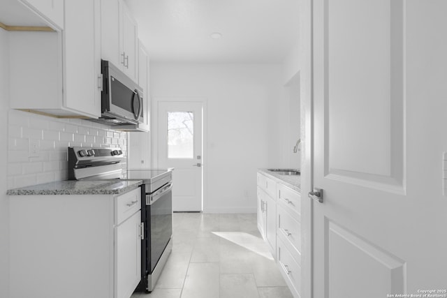 kitchen with sink, white cabinetry, light stone counters, tasteful backsplash, and appliances with stainless steel finishes