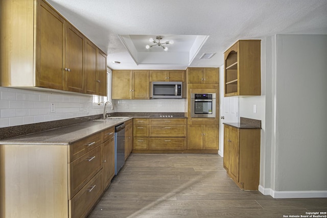 kitchen featuring sink, tasteful backsplash, wood-type flooring, a tray ceiling, and stainless steel appliances