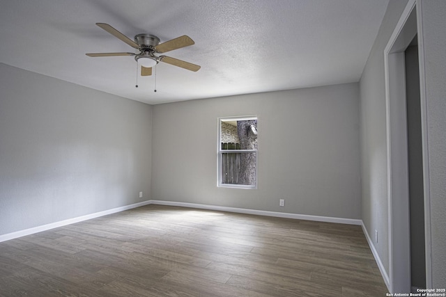 empty room with a textured ceiling, dark wood-type flooring, and ceiling fan