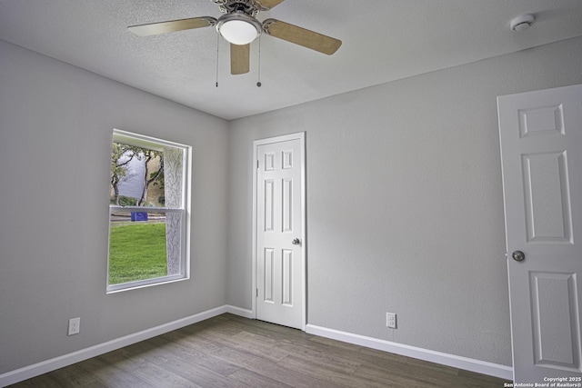 empty room with ceiling fan, a textured ceiling, wood-type flooring, and a healthy amount of sunlight