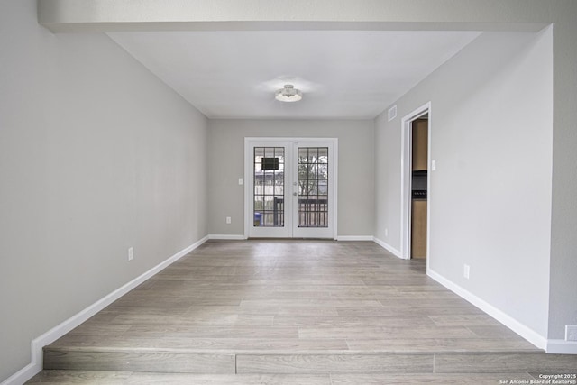 spare room featuring french doors and light hardwood / wood-style flooring