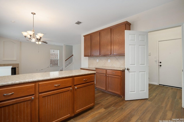 kitchen featuring dark wood-type flooring, decorative light fixtures, a chandelier, and decorative backsplash