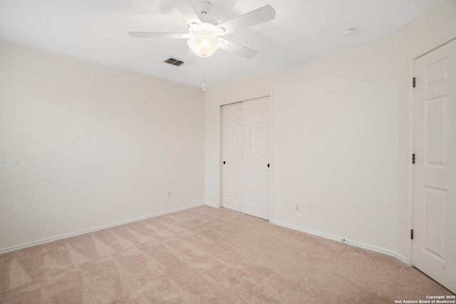 unfurnished bedroom with ceiling fan, a closet, and light carpet